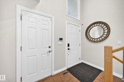 Entryway featuring two paneled doors with white trim, wood-finish flooring, and a decorative arched transom window - 