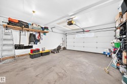 Spacious garage featuring a concrete floor, overhead lighting, and an automatic garage door opener - 