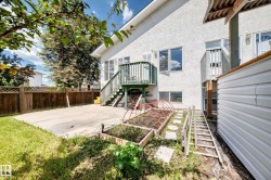 Rear exterior featuring a concrete patio, wooden privacy fencing, and two raised garden beds - 