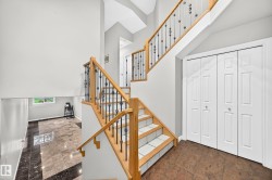 Two-story entryway with a wood and wrought iron staircase, light gray walls, and contrasting tile flooring - 