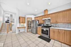 Bright kitchen featuring light wood cabinetry, stainless steel appliances, a tile backsplash, and ceramic tile flooring - 
