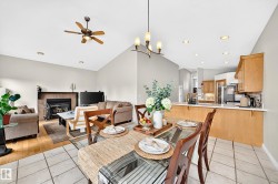 Vaulted ceilings highlight this open-concept living area with a fireplace and wood-finish flooring - 