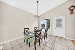 Vaulted ceiling dining area featuring tile flooring, a clear paneled exterior door, and a multi-pane window - 