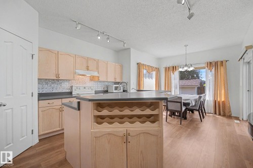 Open-concept kitchen featuring light wood cabinetry, a tiled backsplash, and dark countertops - 262 Dunvegan Road, Edmonton, AB 