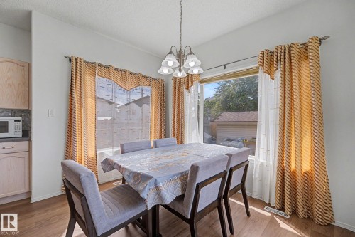 Dining area featuring wood-finish flooring, two large windows, and a multi-bulb chandelier - 262 Dunvegan Road, Edmonton, AB 