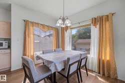 Dining area featuring wood-finish flooring, two large windows, and a multi-bulb chandelier - 