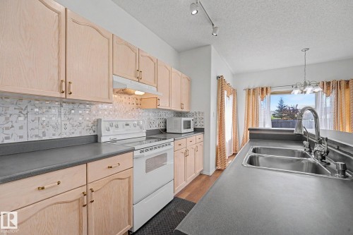 Functional kitchen featuring ample cabinetry, a mosaic tile backsplash, and a double basin stainless steel sink with a high-arch faucet - 262 Dunvegan Road, Edmonton, AB 