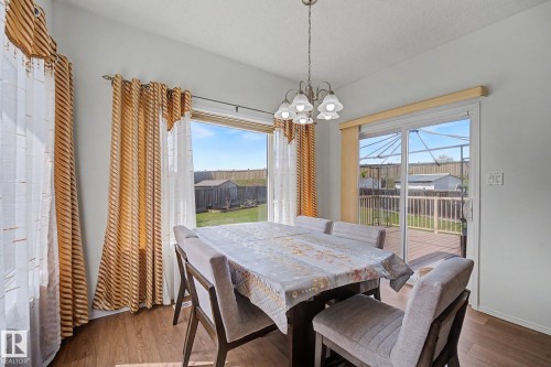 Dining area featuring wood-finish flooring, a contemporary chandelier, and a sliding glass door opening to an outdoor deck - 262 Dunvegan Road, Edmonton, AB 