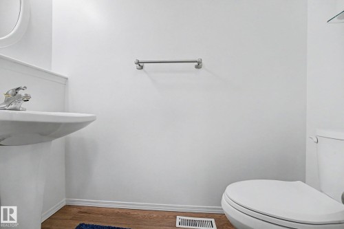 Pedestal sink with chrome faucet hardware, white toilet, and wood-finish flooring - 262 Dunvegan Road, Edmonton, AB 