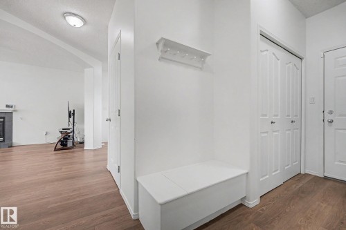 Entryway featuring wood-finish flooring, a built-in storage bench, and a wall-mounted coat rack - 262 Dunvegan Road, Edmonton, AB 