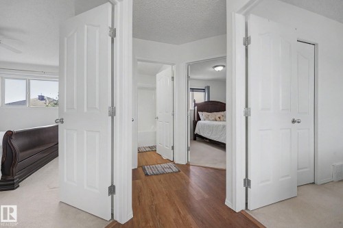Hallway featuring wood-finish flooring, white paneled doors, and direct access to multiple rooms - 262 Dunvegan Road, Edmonton, AB 
