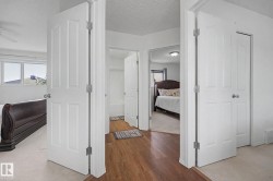 Hallway featuring wood-finish flooring, white paneled doors, and direct access to multiple rooms - 