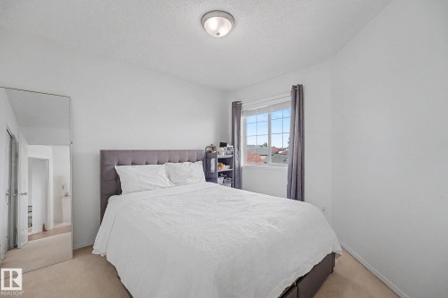Carpeted room featuring a double-paned window with grey curtains, a flush-mount ceiling light fixture, and light-colored walls - 262 Dunvegan Road, Edmonton, AB 