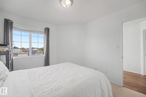 Bright bedroom featuring a grid-pattern window, white walls, and a flush-mount ceiling light - 262 Dunvegan Road, Edmonton, AB 