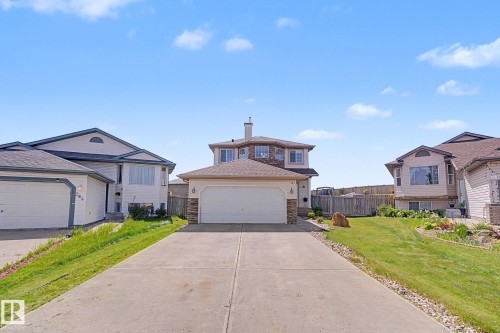 Two-story residence featuring a concrete driveway and an attached two-car garage with a white overhead door - 262 Dunvegan Road, Edmonton, AB 