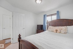 Carpeted bedroom featuring a window with blue curtains, a ceiling-mounted light fixture, and two panel doors - 