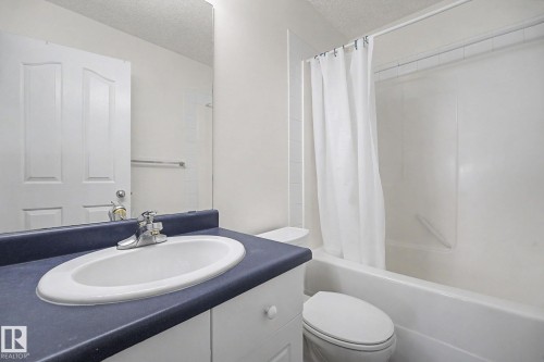Bathroom vanity with an integrated sink, chrome faucet, and dark countertop - 262 Dunvegan Road, Edmonton, AB 