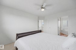 Carpeted bedroom featuring a ceiling fan with integrated lighting, white walls, and a white paneled door - 