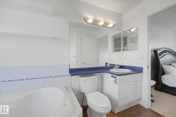 Bathroom featuring a built-in tub, white toilet, and a vanity with a white basin sink and blue countertop - 