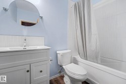 Bathroom featuring a white vanity with integrated sink, chrome faucet, and a circular mirror - 