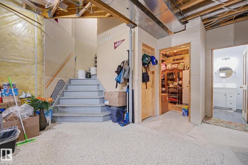 Lower level featuring an exposed ceiling, light gray painted stairs with a wood handrail, and carpet flooring - 262 Dunvegan Road, Edmonton, AB 