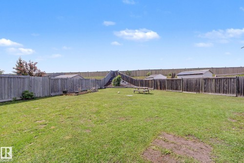 Expansive backyard featuring a large grassy area, privacy fencing, and two storage sheds - 262 Dunvegan Road, Edmonton, AB 