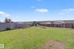 Expansive backyard featuring a large grassy area, privacy fencing, and two storage sheds - 