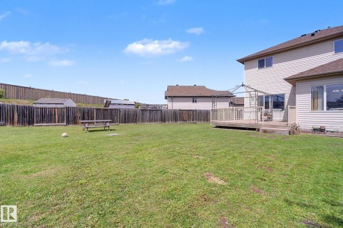 Expansive green lawn backyard featuring a wooden privacy fence, multi-level wood deck, and vinyl siding exterior - 262 Dunvegan Road, Edmonton, AB 