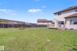 Expansive green lawn backyard featuring a wooden privacy fence, multi-level wood deck, and vinyl siding exterior - 