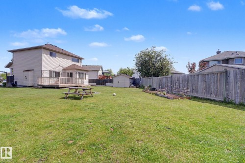 Expansive grassy backyard featuring a multi-level wood deck with a built-in gazebo, a detached storage shed, and perimeter fencing - 262 Dunvegan Road, Edmonton, AB 