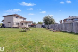 Expansive grassy backyard featuring a multi-level wood deck with a built-in gazebo, a detached storage shed, and perimeter fencing - 