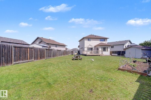 Expansive backyard featuring a manicured lawn, a wooden privacy fence, a raised garden bed, a rear deck, and a detached shed - 262 Dunvegan Road, Edmonton, AB 