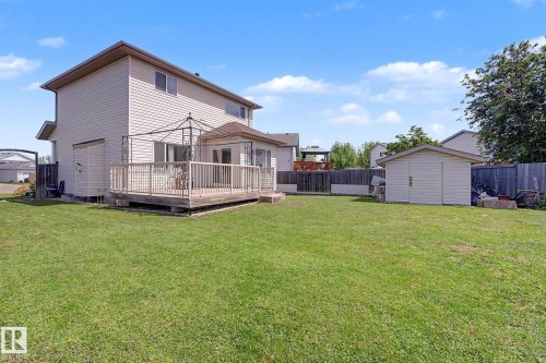 Expansive backyard featuring a large wooden deck with railing, direct access to the interior via double French doors, and a detached storage shed - 262 Dunvegan Road, Edmonton, AB 
