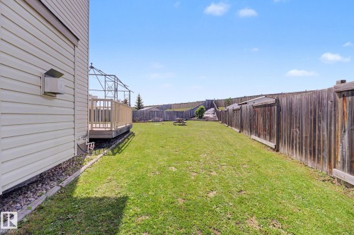 Expansive rear yard featuring a wood privacy fence, a wooden deck with railing, and a manicured lawn - 262 Dunvegan Road, Edmonton, AB 