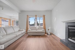 Living area featuring wood-finish flooring and a tiled fireplace with a mantel - 
