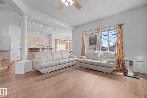 Spacious living area featuring wood-finish flooring, a ceiling fan, and architectural column detailing - 262 Dunvegan Road, Edmonton, AB 