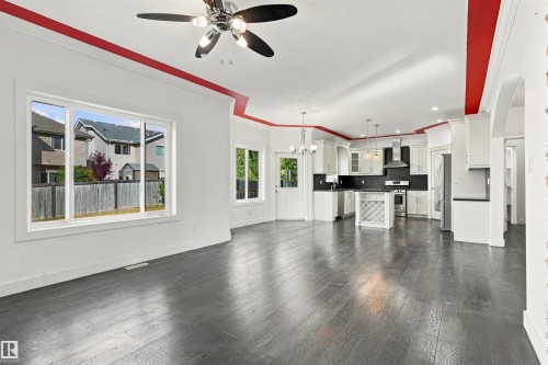 Open-concept living space with dark wood-finish flooring, white walls, and a contemporary ceiling fan - 1660 Malone Way Nw, Edmonton, AB 
