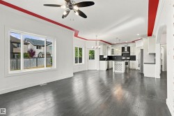 Open-concept living space with dark wood-finish flooring, white walls, and a contemporary ceiling fan - 