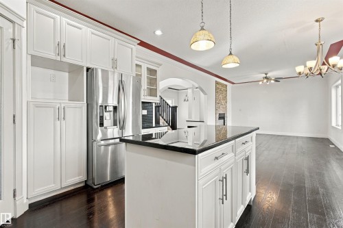 Kitchen island with a dark countertop, white cabinetry with silver-tone hardware, and dark wood-finish flooring - 1660 Malone Way Nw, Edmonton, AB 