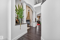 Hall featuring ornate columns, arched walkways, dark wood-style floors, and a high ceiling - 