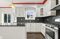 White cabinetry, black countertops, tile backsplash, and stainless steel appliances - 