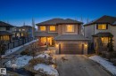 View of front of property featuring roof with shingles, stone siding, driveway, a garage, and a porch - 1660 Malone Way, Edmonton, AB 