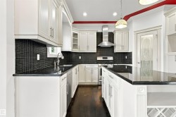Kitchen featuring white cabinetry, dark countertops, a tile backsplash, stainless steel appliances, and dark wood-finish flooring - 