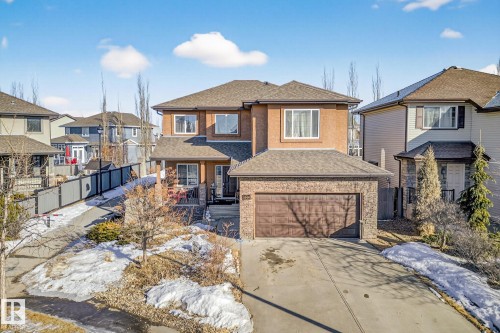View of front of home with a shingled roof, driveway, a residential view, a garage, and stone siding - 1660 Malone Way, Edmonton, AB 