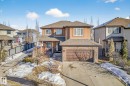 View of front of home with a shingled roof, driveway, a residential view, a garage, and stone siding - 1660 Malone Way, Edmonton, AB 