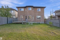 Expansive backyard featuring a wooden privacy fence, a multi-level wooden deck, and a stucco exterior - 
