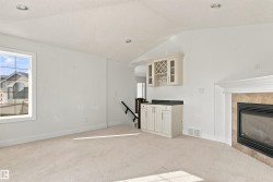 Vaulted ceiling, built-in cabinetry with counter, fireplace with tile surround, recessed lighting, and a square window - 