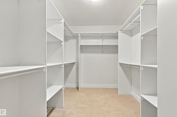 Walk-in closet featuring extensive built-in shelving, multiple hanging rods, and neutral carpet flooring - 