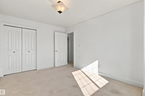 Neutral tone wall paint, flush mount ceiling light fixture, white interior doors, and carpet flooring - 1660 Malone Way Nw, Edmonton, AB 