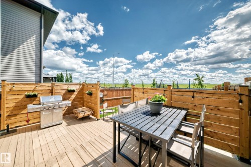 Expansive outdoor deck featuring wood-finish flooring and a horizontal slat privacy fence - 93 Richmond Link, Fort Saskatchewan, AB 
